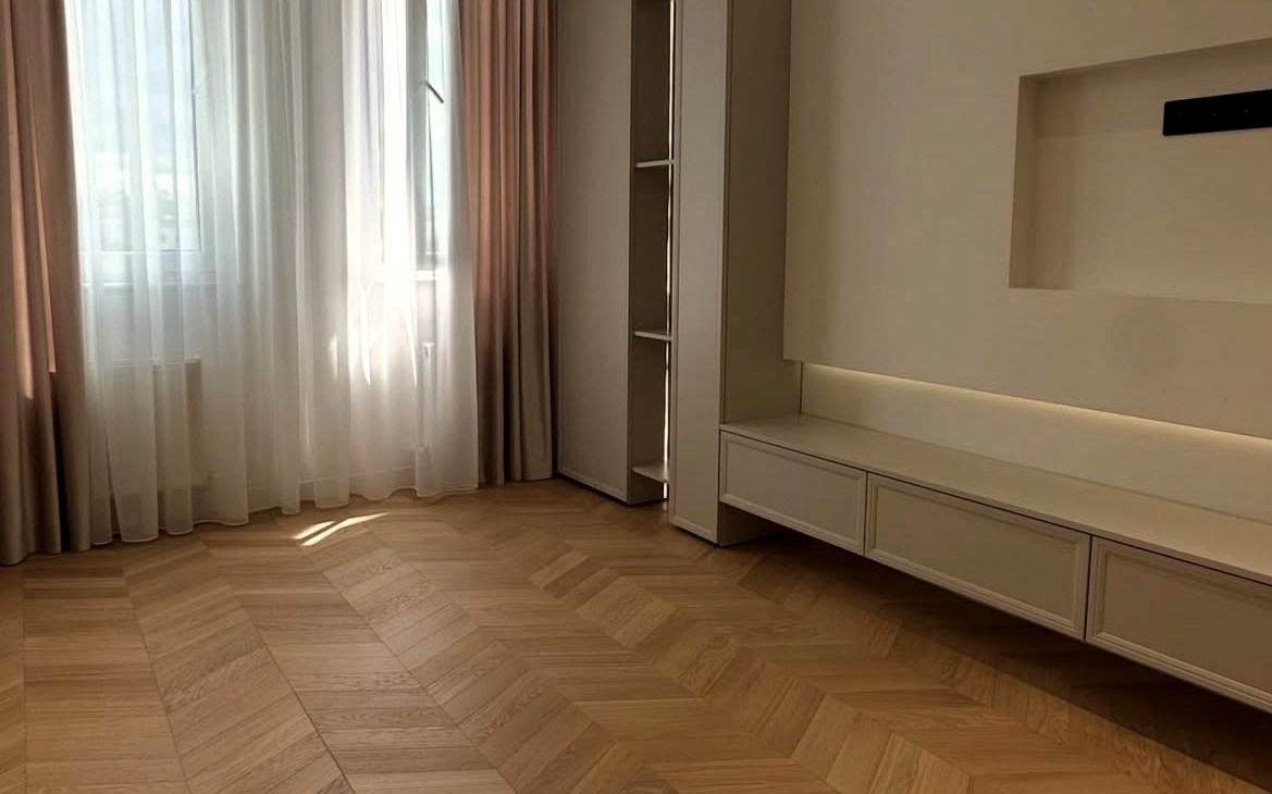 Soggiorno con parquet a spina francese e parete attrezzata con luce LED